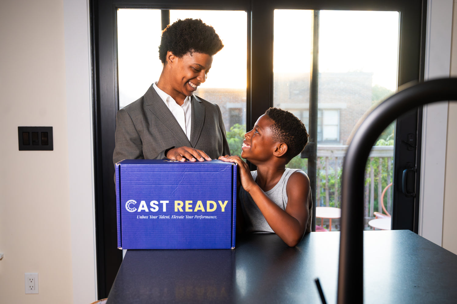 Parent and child smiling and unboxing a CastReady acting education kit together at home, highlighting accessibility and family connection.